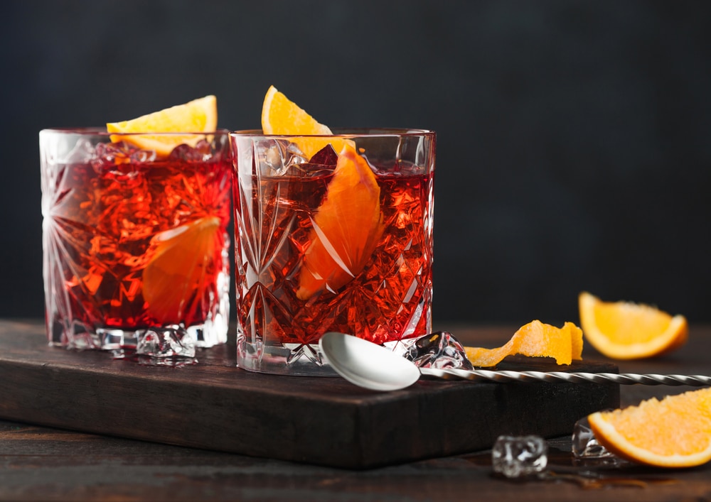 Negroni cocktail in crystal glasses with orange slice and fresh raw oranges 