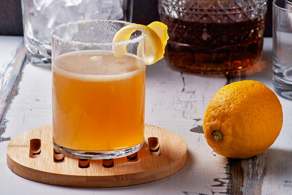 Whiskey sour cocktail in a rocks glass with ice, garnished with a slice of orange and a cherry