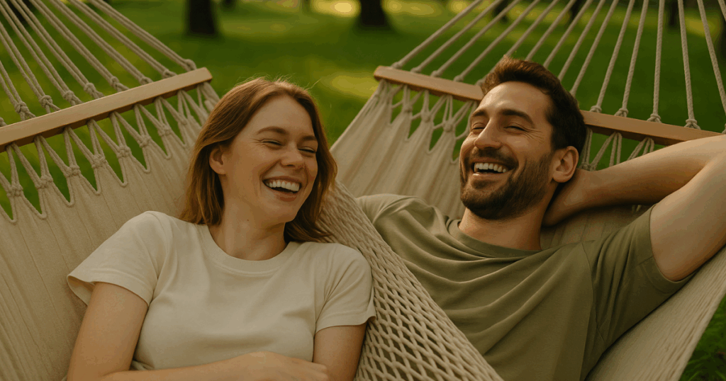 Couple laying side-by-side on matching cotton hammocks in a sunny park