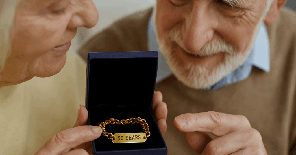 Couple looking at gold jewellery engraved with “50th Anniversary”