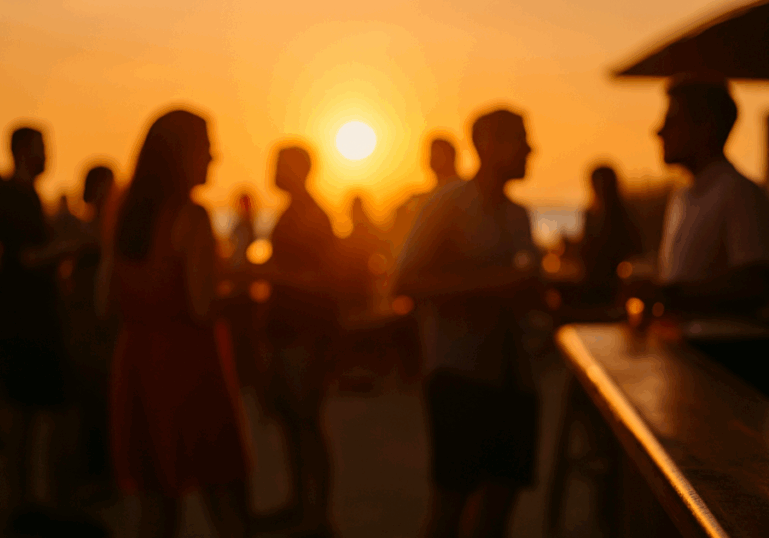 Blurry silhouettes of people socialising using their best pickup lines at an outdoor bar during sunset, with a warm orange sky in the background.